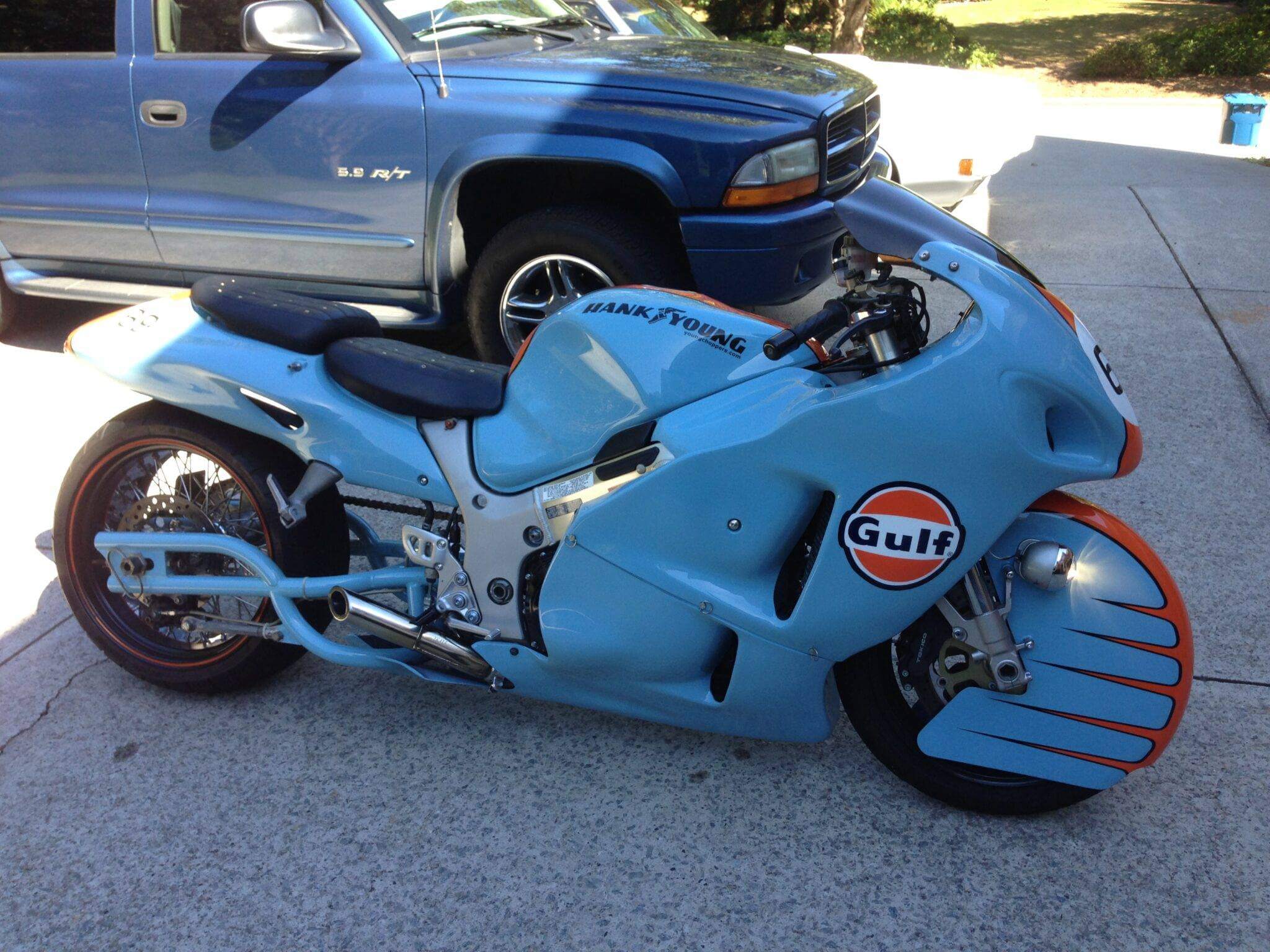 A sleek blue custom motorcycle with Gulf racing decals parked outdoors.