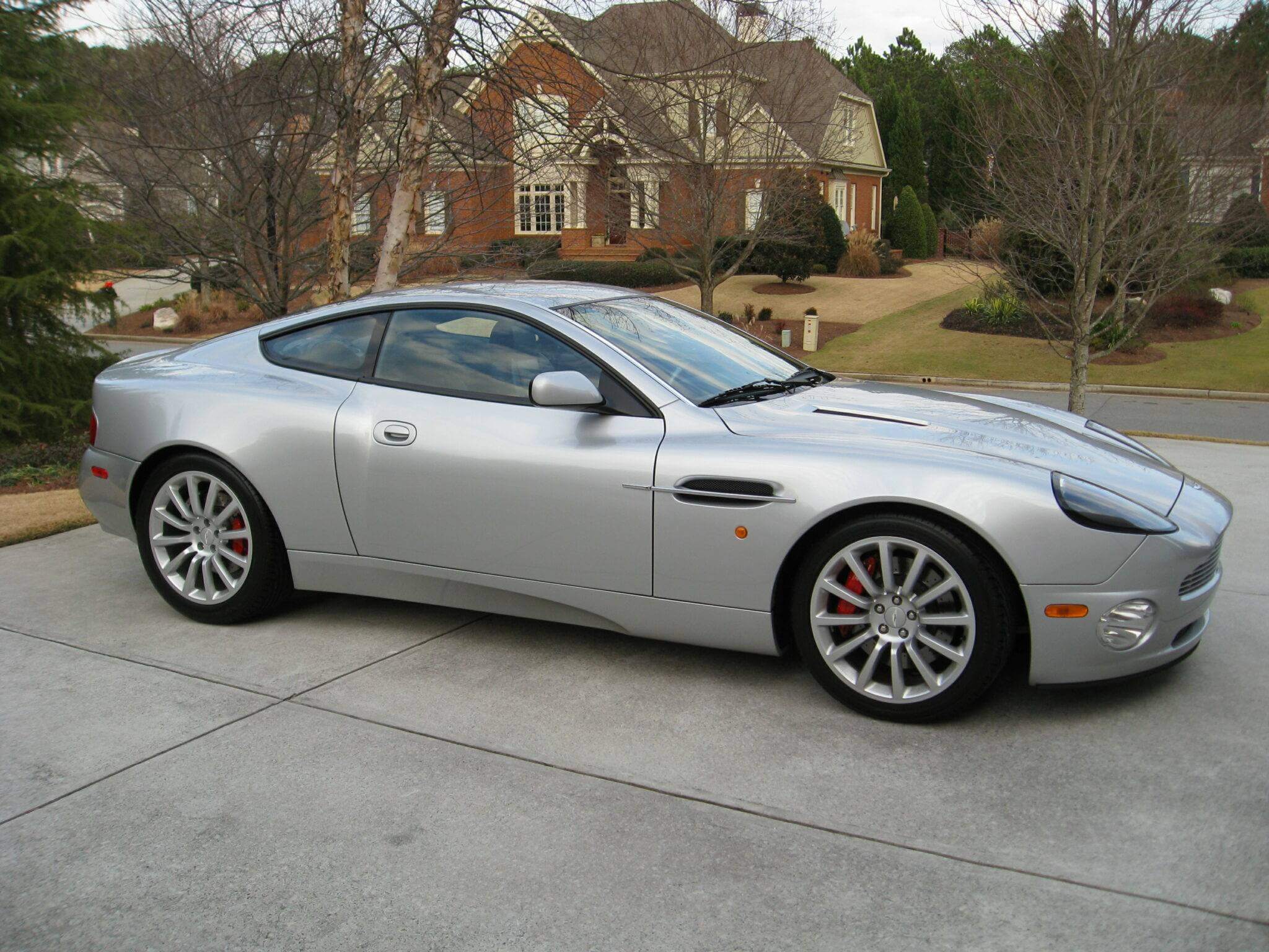 Silver luxury sports car parked on driveway in front of a house.