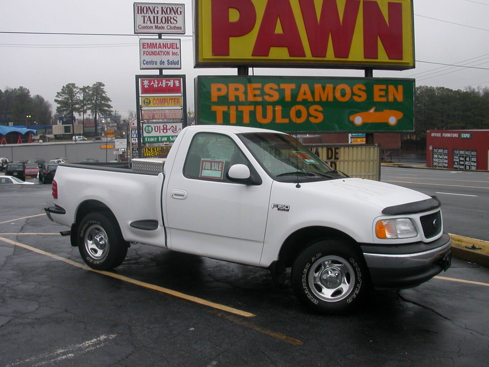 White pickup truck parked outside a pawn shop with Spanish signage.