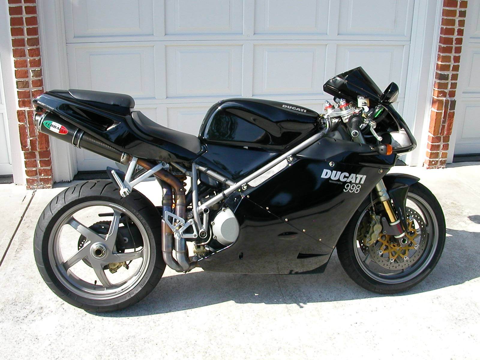 A sleek black Ducati sport motorcycle parked in front of a garage.