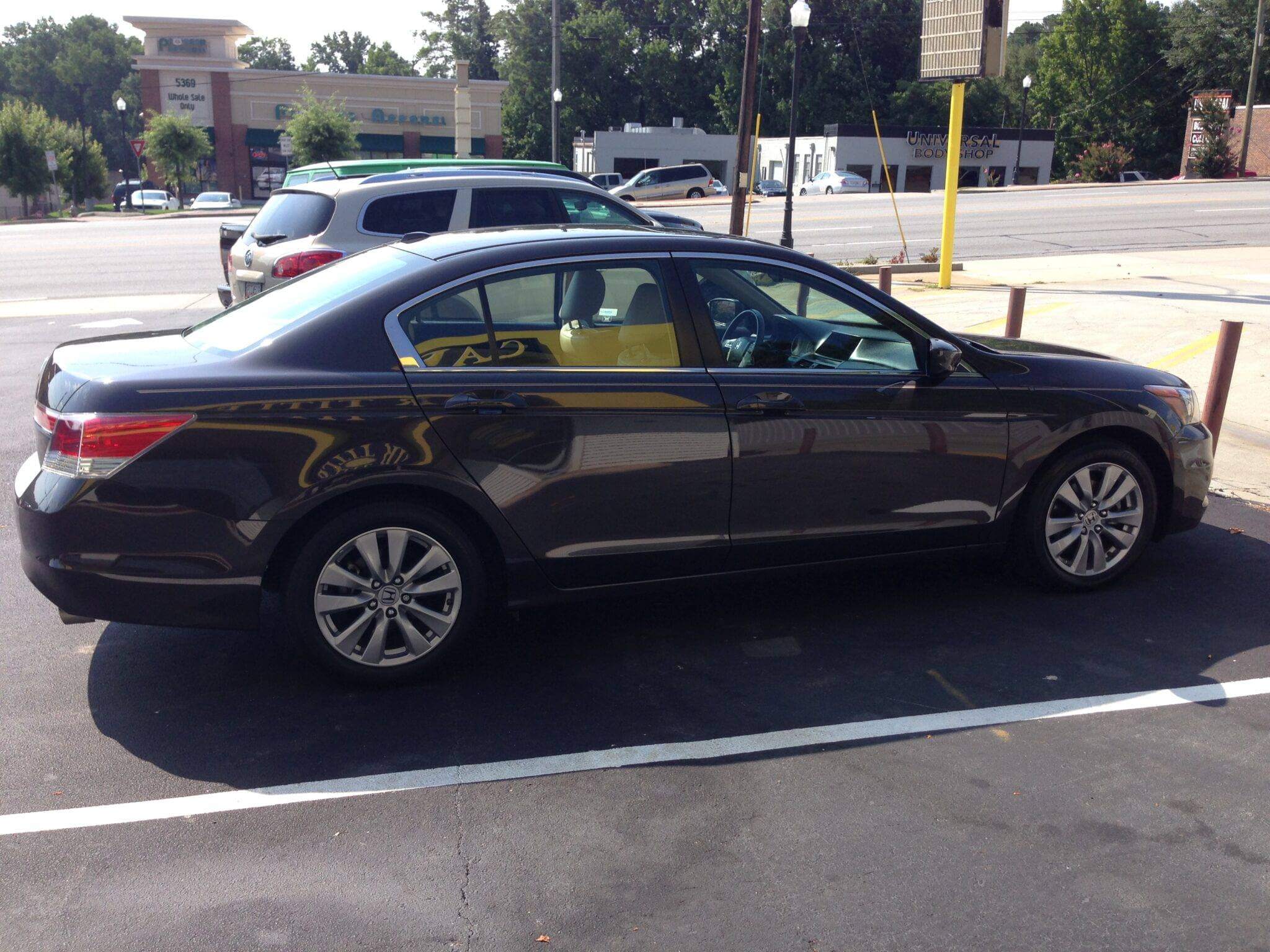 A dark-colored sedan parked in a lot on a sunny day.