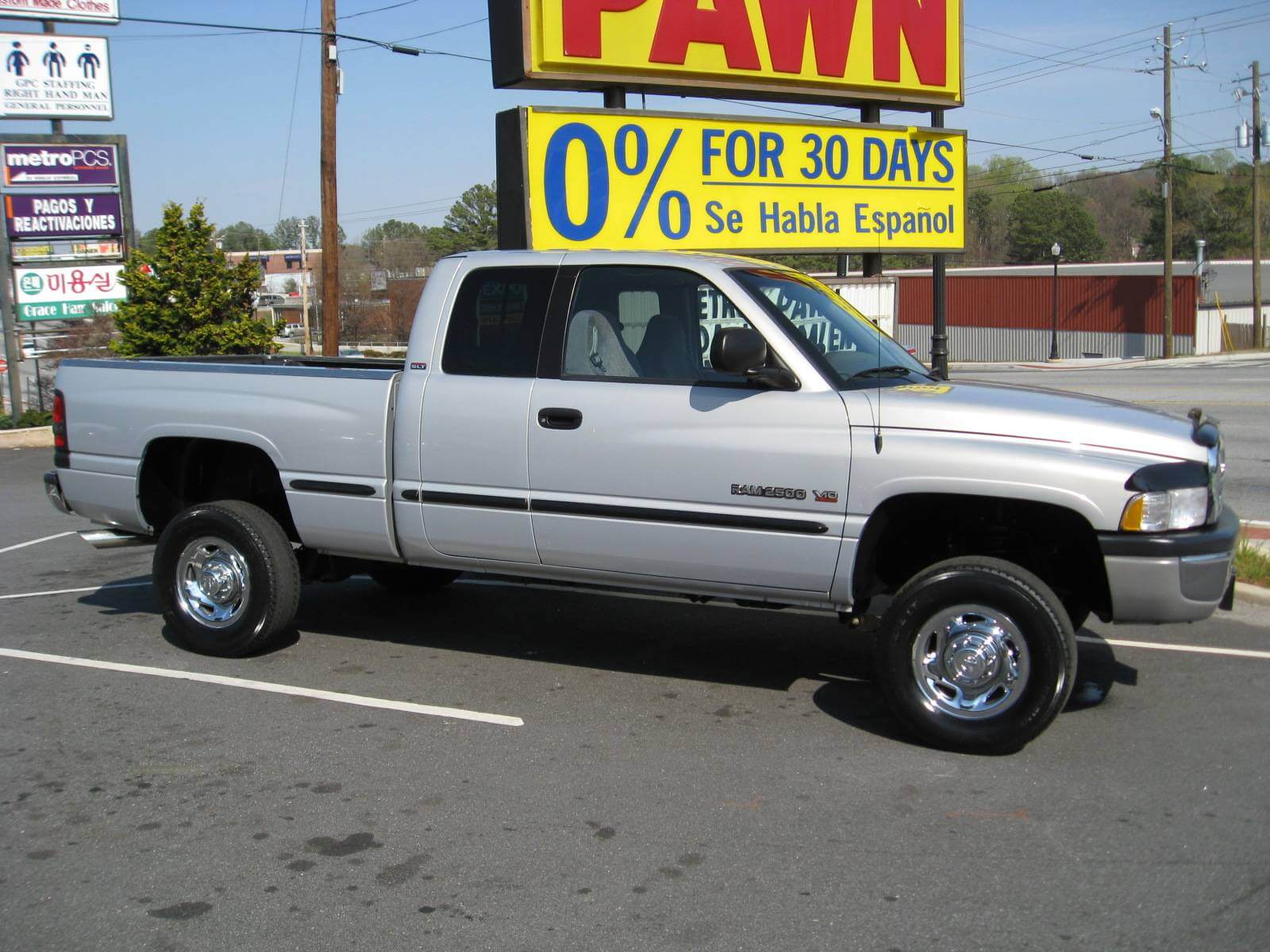 Silver pickup truck parked near a pawn shop with a 0% financing sign.