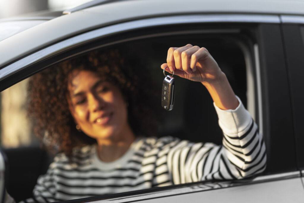 Woman happily holding car keys inside a vehicle.